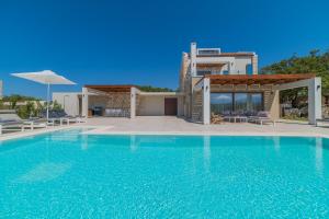 a villa with a swimming pool in front of a house at Rethymno Villas in Prinés