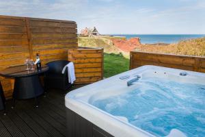 a hot tub on a deck with a table and the ocean at Bayswell Park Hotel in Dunbar
