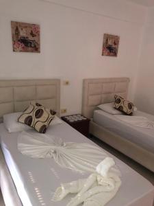 Dos camas en una habitación con toallas. en Hotel Soan en Sarandë