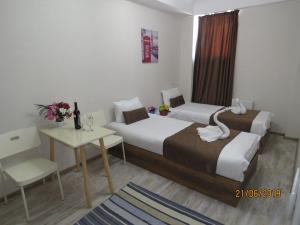 una camera d'albergo con 2 letti, un tavolo e una scrivania di Atlas Hotel a Tbilisi City
