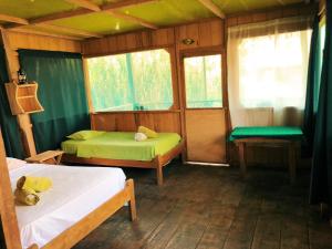 a small room with two beds and a window at Iguana Lodge Perú in Iquitos