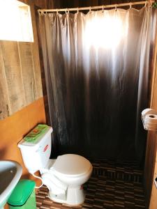 a bathroom with a toilet and a black shower curtain at Iguana Lodge Perú in Iquitos