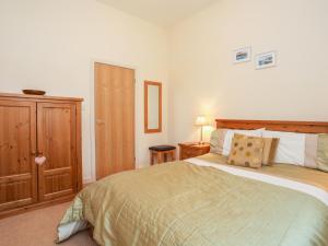 a bedroom with a bed and a wooden cabinet at Gwel y Rhos in Llanfairpwllgwyngyll