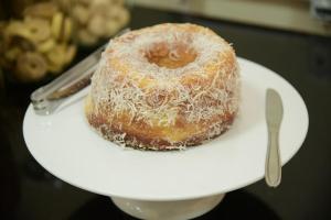 a doughnut sitting on a white plate with a fork at TOPÁZIO IMPERIAL HOTEL in Itaúna
