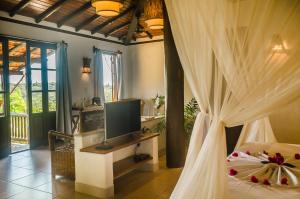 a bedroom with a bed with a tv and curtains at Pousada Mundo Verde in Trancoso