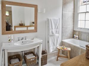 a bathroom with a sink and a tub and a mirror at Artisan Cottage in Chippenham