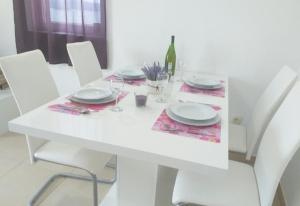 a white table with plates and wine glasses on it at Apartman Pazin in Klek