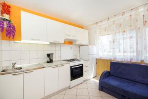 una cocina con armarios blancos y una silla azul en Apartments Mise, en Makarska 15 fotos más