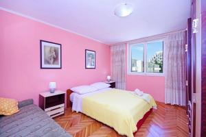 a pink bedroom with a bed and a couch at Apartments Mise in Makarska