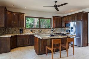 uma cozinha com armários de madeira e um frigorífico de aço inoxidável em Fort Walker (Beachfront House) em Rivas