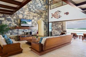 a living room with wooden furniture and a stone wall at Fort Walker (Beachfront House) in Rivas