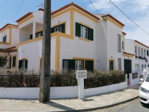 a white and yellow house with a sign in front of it at Vivenda Framboesa in Vila Nova de Milfontes