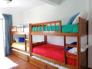 two bunk beds in a room with a red mattress at Vivenda Framboesa in Vila Nova de Milfontes