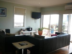 a living room with a couch and a tv at OCEAN VIEWS in Warrnambool