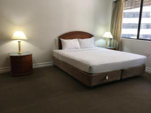 a hotel room with a bed and a lamp at Great Southern Hotel Brisbane in Brisbane