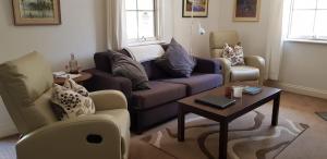 a living room with a couch and two chairs and a table at Amy's House Bed & Breakfast in Auburn
