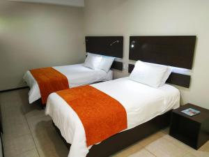 Habitación de hotel con 2 camas con sábanas de color naranja y blanco en Monte Selva Spa Termal en Baños