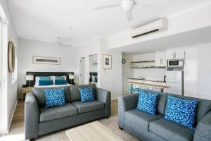 a living room with two couches and a kitchen at Mantra PortSea in Port Douglas