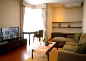 sala de estar con sofá y TV en Siam Bright Suite, en Bangkok