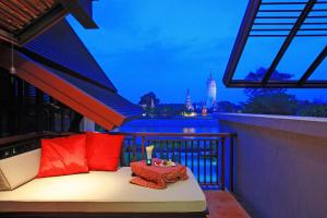 a balcony with a bed with red pillows and a table at iuDia Hotel in Phra Nakhon Si Ayutthaya