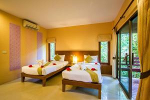 Sunda Resort في شاطيء آونانغ: سريرين في غرفة بجدران صفراء ونوافذ