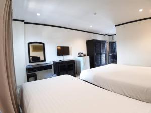 a bedroom with two beds and a mirror and a tv at Golden Tulip Essential Pattaya in North Pattaya