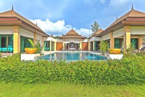 
a large white house with a pool of water in front of it at Ataman Luxury Villas SHA Plus in Ko Kho Khao
