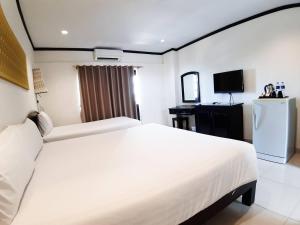 a bedroom with a large white bed and a television at Golden Tulip Essential Pattaya in Pattaya North