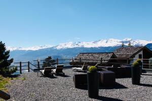eine Terrasse mit Stühlen und Bergen im Hintergrund in der Unterkunft Les Mazots de la Source & Spa in Vercorin