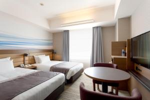 a hotel room with two beds and a table and a tv at Haneda Excel Hotel Tokyu Haneda Airport Terminal 2 in Tokyo