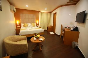 a hotel room with a bed and a chair and a table at BROAD BEAN KANNUR in Kannur