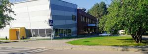 um edifício com um carro estacionado em frente em Ignalinos sporto ir pramogų centras em Ignalina