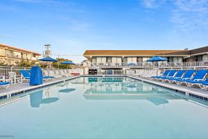 - une piscine avec des chaises et des parasols bleus dans l'établissement Harris House by the Beach, à Ocean City