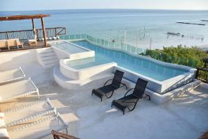 a swimming pool with two chairs and the beach at Spirit Holbox in Holbox Island