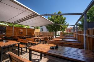 a patio with wooden tables and benches and an umbrella at Penzion U Gigantu in Plzeň