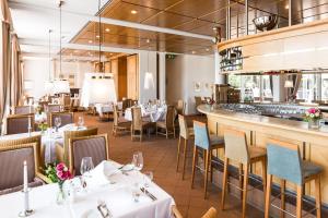 ein Restaurant mit Tischen und Stühlen und eine Bar in der Unterkunft Golfhotel & Restaurant Lindenhof in Bad Vilbel
