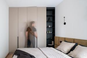 a man standing next to a bed in a bedroom at Modern boutique apartment in the city center in Druskininkai