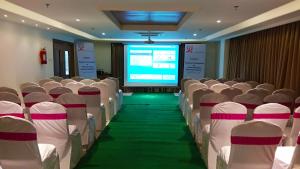 a conference room with white chairs and a projection screen at Hotel Smart City Park Inn in Tada