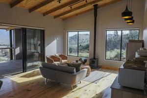 a living room with a couch and chairs and windows at Opstal Stay in Rawsonville