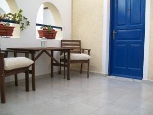 a table and chairs with a blue door at Villa Spyros Santorini in Perissa
