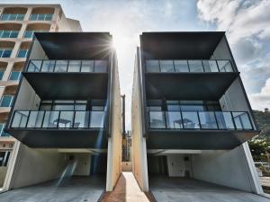 two buildings with the sun shining between them at Condominium NOOSA in Nago