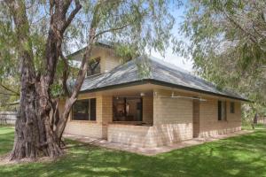 
a large wooden house with a tree in front of it at Siesta Park Holiday Resort in Busselton
