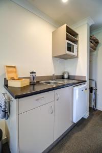 a small kitchen with a sink and a microwave at Hanmer Springs Retreat in Hanmer Springs