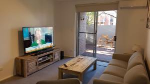 - un salon avec une télévision, un canapé et une table dans l'établissement North Adelaide Apartment, à Adélaïde