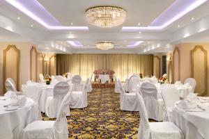 a banquet hall with white tables and chairs and a chandelier at Hawthorn Suites by Wyndham Al Khobar in Al Khobar