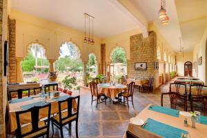 un ristorante con tavoli e sedie in una stanza di WelcomHeritage Shivavilas Palace, HAMPI a Hospet