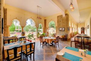a restaurant with tables and chairs in a room at WelcomHeritage Shivavilas Palace, HAMPI in Hospet