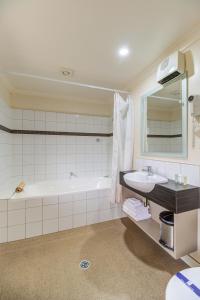 a bathroom with a tub and a sink and a mirror at Hanmer Springs Retreat in Hanmer Springs