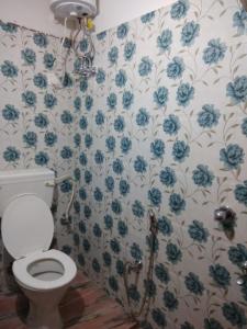 a bathroom with a toilet and blue flowers on the wall at Babusona Homestay in Jaldapara in Mādāri Hāt