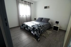 1 dormitorio con 1 cama con manta blanca y negra en Coin Zen et Reposant, en Le Tampon